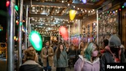 FILE - People make their way through local restaurants during the coronavirus pandemic in New York City, March 11, 2021. 