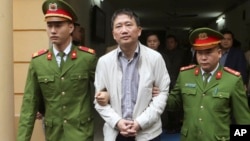 FILE - Trinh Xuan Thanh, center, is led out of a courtroom by police officers in Hanoi, Vietnam, Monday, Jan. 22, 2018. Germany accused Vietnam of kidnapping Thanh from a Berlin park in July, the charge Vietnam denied saying Thanh turned himself in to police voluntarily. (An Dang/Vietnam News Agency via AP)