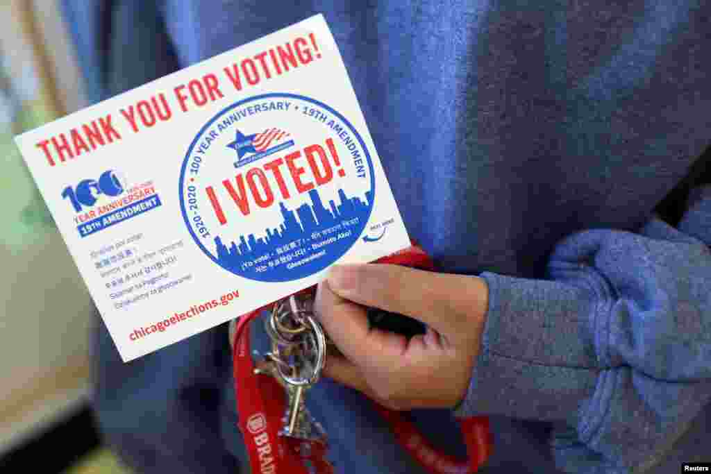 A person holds a sticker at a polling station in Deja Hue Art on Election Day in Chicago, Illinois, Nov. 3, 2020. 
