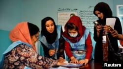 FILE - Afghan election commission workers count ballot papers for the presidential election in Kabul, Afghanistan Sept. 28, 2019.