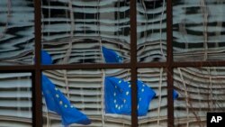 European Union flags are reflected in a window of the European Council in Brussels, Dec. 19, 2020. The European Union and the United Kingdom were making a "last attempt" to clinch a post-Brexit trade deal Saturday.
