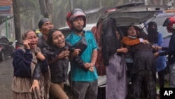 People react as the body of a relative is retrieved from the ruin of a building at an area affected by an earthquake in Mamuju, West Sulawesi, Indonesia, Jan. 15, 2021.