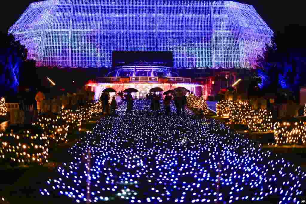 People walk through a Christmas light trail during a lighting test of the Christmas Garden in the Botanical Garden in Berlin, Germany.