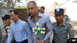Philip Blackwood, second right, general manager of VGastro Bar, walks with bar owner Tun Thurein, second left, and its manager, Htut Ko Ko Lwin, seen behind Blackwood, upon arrival for their trial at a township court, Feb. 17, 2015.