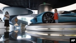 A child pose for photos near a race car displayed at the NIO flagship store in Beijing on Aug. 20, 2020. 