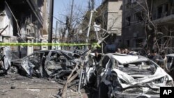 Damaged vehicles are seen at the site after two explosions near the intelligence center building in Damascus, March 17, 2012. 