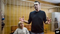 Russian opposition leader Alexei Navalny gestures while speaking, as his lawyer Olga Mikhailova listens, in court in Moscow, Russia, March 27, 2017. 
