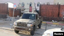 Seorang anggota pasukan keamanan yang setia kepada pemerintah Libya yang didukung PBB mengendarai pickup di penjara Al-Hadba yang rusak saat baku tembak dengan faksi saingan di distrik Abu Salim, di Tripoli, Libya, 28 Mei 2017. (Foto: Hani Amara/Reuters)