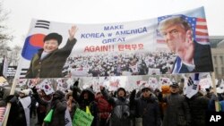 FILE - A banner showing pictures of impeached South Korean President Park Geun-hye and U.S. President Donald Trump is displayed as supporters of Park wave flags of the United States and South Korea during a rally opposing her impeachment in Seoul, South Korea.