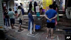 People stand in line maintaining physical distance to buy grocery outside a store during the coronavirus pandemic in Mumbai, India, Wednesday, March 25, 2020. (AP Photo/Rajanish Kakade)