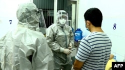 Medical personnel wearing protective suits interact with patients who tested positive for the coronavirus at Cho Ray hospital in Ho Chi Minh City, Jan. 23, 2020.