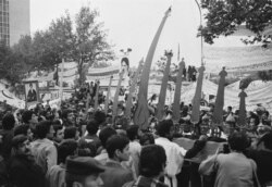 FILE - Religious symbols are held up outside the U.S. Embassy gates in Tehran, Iran, where students hold American hostages, on Nov. 28, 1979.