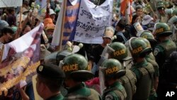 Cambodian riot policemen block protesters from Boeung Kak lake villager, during a protest rally to mark the World Women Day, in Phnom Penh, Cambodia, Friday, March. 8, 2013. Hundreds of protesters from Boeung Kok lake on Friday staged a rally to demand the release a villager Yoam Bopha, who was arrested by local authorities after she protested over compensation for loss of her house due to a new luxury housing development. (AP Photo/Heng Sinith)