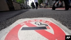 Peringatan larangan merokok di Tokyo dalam tulisan Jepang: "Dilarang Merokok di Jalanan, Denda 2.000 yen ($ 25.29)". (AP Photo/Shizuo Kambayashi)