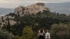 FILE - People visit the Pnyx Hill in Athens overlooking the ancient Acropolis, May 29, 2020.