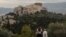 FILE - People visit the Pnyx Hill in Athens overlooking the ancient Acropolis, May 29, 2020.