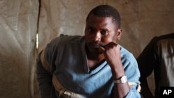 Elected chief of a displacement camp, Witonze Nzambonipa, talks during an interview in Mweso, DRC, Jan. 27, 2015. The wobbly white tarp tents once constructed for people fleeing a violent Rwandan Hutu rebel group have gradually been replaced by more solid huts of branches, banana leaves and mud. 