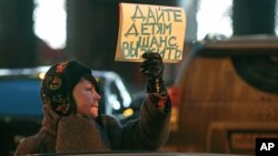 A woman opposing a bill that would ban adoptions of Russian children by Americans holds a sign reading 'Give the children a chance to live' during a picket at the entrance of the State Duma, in Moscow, Russia, December 21, 2012.