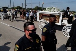 Police officers walk next to the horse-drawn carriage carrying the casket containing the body of George Floyd to Houston Memorial Gardens cemetery in Pearland, Texas, June 9, 2020.