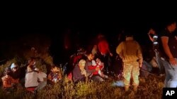 FILE - In this photo released by the Lebanese Army official website, Lebanese troops stand next to Syrian migrants in the northern region of Akkar near the border with Syria, Lebanon.
