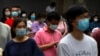 Parents and relatives wearing face masks to protect against the coronavirus wait for students to finish taking national college entrance exams on the final day of testing in China, July 10, 2020, in Beijing.
