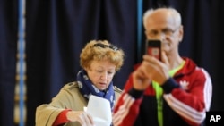 A man takes photos as a woman casts her vote in Bucharest, Romania, Nov. 10, 2019. 