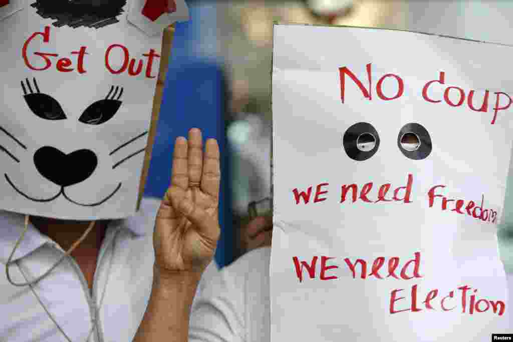 Anti-coup protesters wear paper bags with messages written on them as they flash a three-finger sign during a protest at a shopping mall in Bangkok, June 1, 2014. 