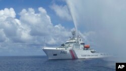 FILE - A Chinese Coast Guard boat approaches a Filipino fishing vessel off Scarborough Shoal in the South China Sea, Sept. 23, 2015.