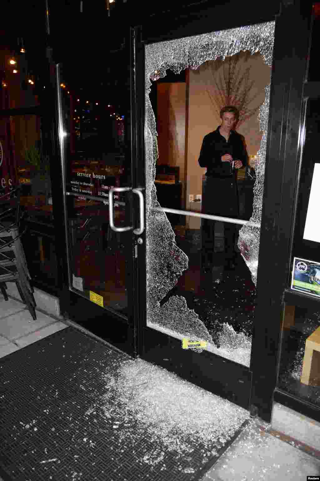 A man looks at broken glass after a riot swept through the area in protest to the election of Republican Donald Trump as President of the United States in Portland, Oregon, Nov. 10, 2016. 