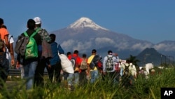Central American migrants begin their morning trek as part of a thousands-strong caravan hoping to reach the U.S. border, as they face the Pico de Orizaba volcano upon departure from Cordoba, Veracruz state, Mexico, Monday, Nov. 5, 2018.
