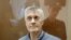 FILE - Founder of the Baring Vostok private equity group Michael Calvey, who was detained on suspicion of fraud, sits inside a defendants' cage as he attends a court hearing in Moscow, Feb. 15, 2019.