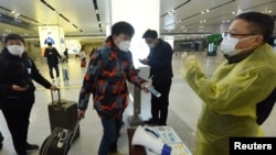 中国浙江省杭州市火车站一名旅客使用手机中的绿色健康码向车站检疫人员显示他的健康状况。（2020年2月17日）