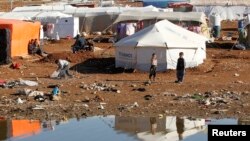 Syrian refugees sit outside their tent at their camp in Amman, Jordan, Dec. 23, 2013. 