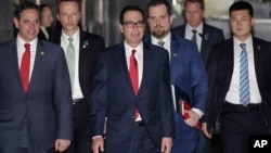 U.S. Treasury Secretary Steven Mnuchin, center, escorted by bodyguards and a delegation leaves a hotel in Beijing, March 29, 2019. 