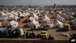 Internally displaced people walk among the tents in a camp in Tabqa city, Raqqa governorate, northern Syria, Dec. 4, 2024.