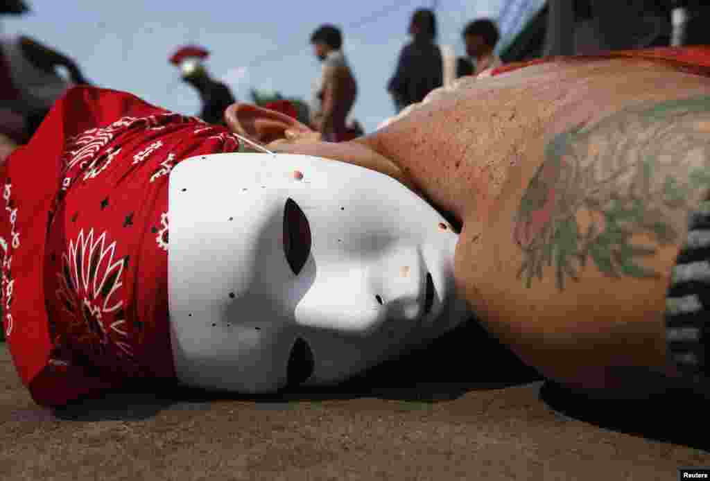 A masked flagellant lies prostrate on the ground as he prays outside a chapel during a Maundy ritual by penitents to atone for sins in Angeles, Pampanga north of Manila.