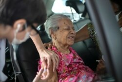 Maria de Lourdes, 101, grimaces as she receives a dose of China's Sinovac Biotech COVID-19 vaccine at a drive-thru vaccination site in the Sambadrome, in Rio de Janeiro, Brazil, Feb. 6, 2021.