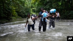 FILE - Haitian migrants wade through a river as they cross the Darien Gap, from Colombia into Panama, hoping to reach the U.S., Oct. 15, 2022. 