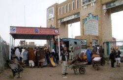 FILE - Families wait to cross the Afghanistan-Pakistan border point in Spin Boldak, Kandahar province, Afghanistan, March 7, 2017.