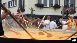  Cooks and volunteers stir eggs on an oversize pan at a Giant Omelet event in Malmedy, Belgium, August 2017.
