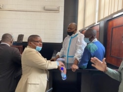 Opposition leader Job Sikhala, wearing personal protective equipment, talks to Harrison Nkomo of Zimbabwe Lawyers for Human Rights, in the courthouse at Harare Magistrate’s Court, Jan. 14, 2021. (Columbus Mavhunga/VOA)