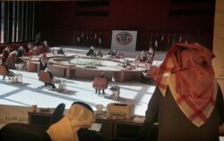 Saudi journalists watch a screen showing the meeting of the 41st Gulf Cooperation Council (GCC) taking place in Al Ula, Saudi Arabia, Jan. 5, 2021.