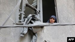 A woman looks out of the window of a building that was damaged during Israeli bombardment at the Al-Daraj neighborhood in Gaza City on May 21, 2024.