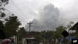 Motorists ride as pyroclastic material from the eruption of Mount Merapi billows in the background in Cangkringan, Yogyakarta, Indonesia, 31 Oct 2010