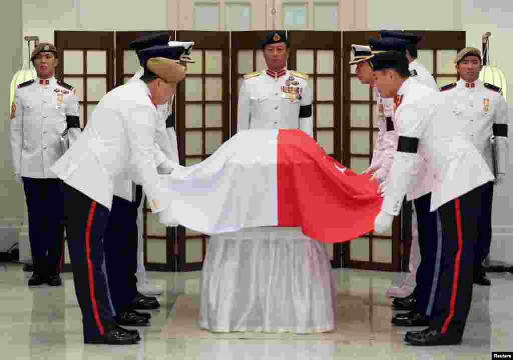 The Honor Guard drapes the Singapore national flag over the coffin of the late first prime minister Lee Kuan Yew in the Istana before he is conveyed to the Parliament House where he will lie in state until Saturday, in Singapore March 25, 2015.