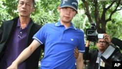 In this Sept. 3, 2012, photo, Vorayuth "Boss" Yoovidhya, center, whose grandfather co-founded energy drink company Red Bull, is escorted by police in Bangkok, Thailand. Vorayuth is accused of killing a Thai police officer in a hit-and-run in 2012, yet he still has not appeared to face charges. (Thai Daily News via AP)