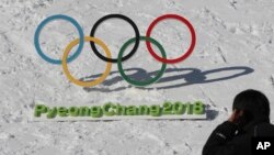 Seorang pria berjalan melewati gelang-gelang Olimpiade dengan tulisan Olimpiade Musim Dingin Pyeongchang 2018, di Pyeongchang, Korea Selatan, 3 Februari 2017.