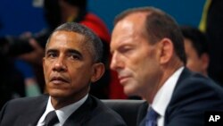 U.S. President Barack Obama listens as Australian Prime Minister Tony Abbott makes opening remarks at the first plenary session of the G20 Summit in Brisbane, Australia Saturday, Nov. 15, 2014.
