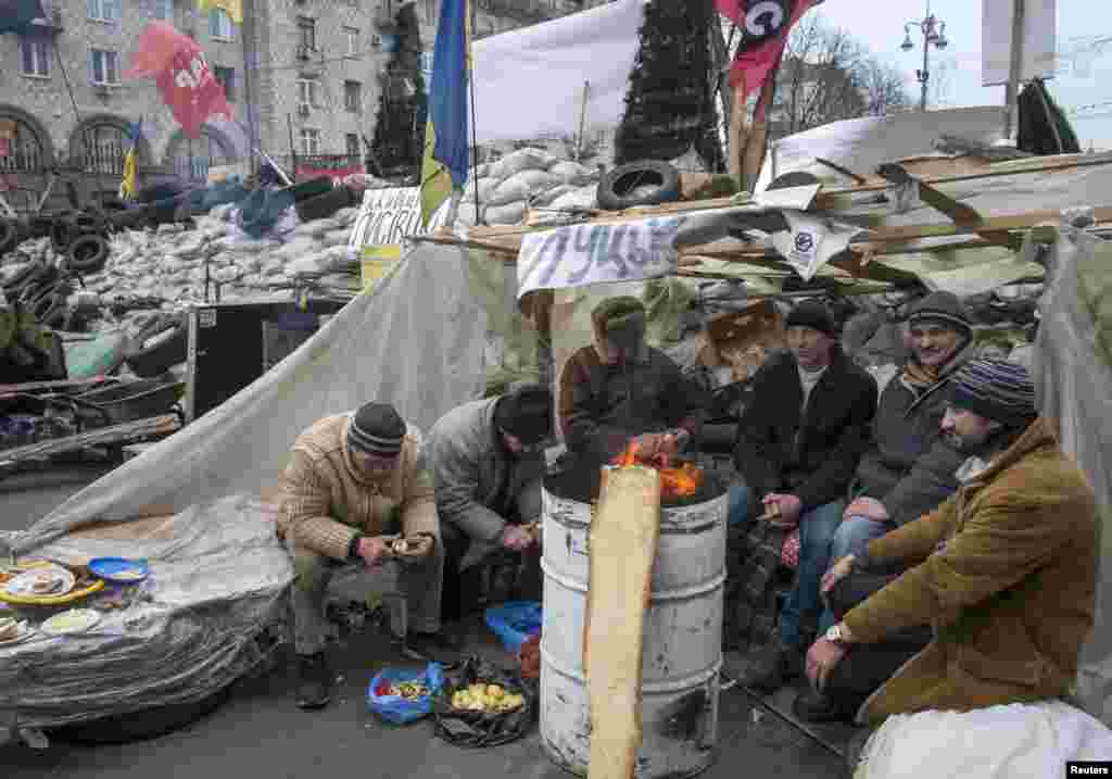 Ukrainian pro-EU demonstrators warm themselves by a fire during a rally in Independence Square, Kyiv, Ukraine, Dec. 20, 2013. 