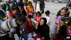 Ziaee Shole, au centre, un professeur d'université, parle aux enfants afghans au port d'Athènes du Pirée, 1er avril 2016.